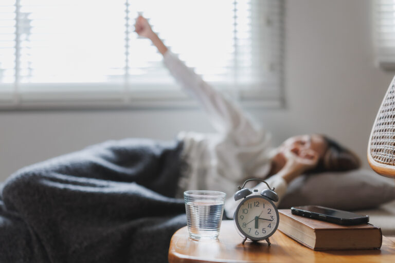 A woman waking up in bed looking exhausted yet alert.