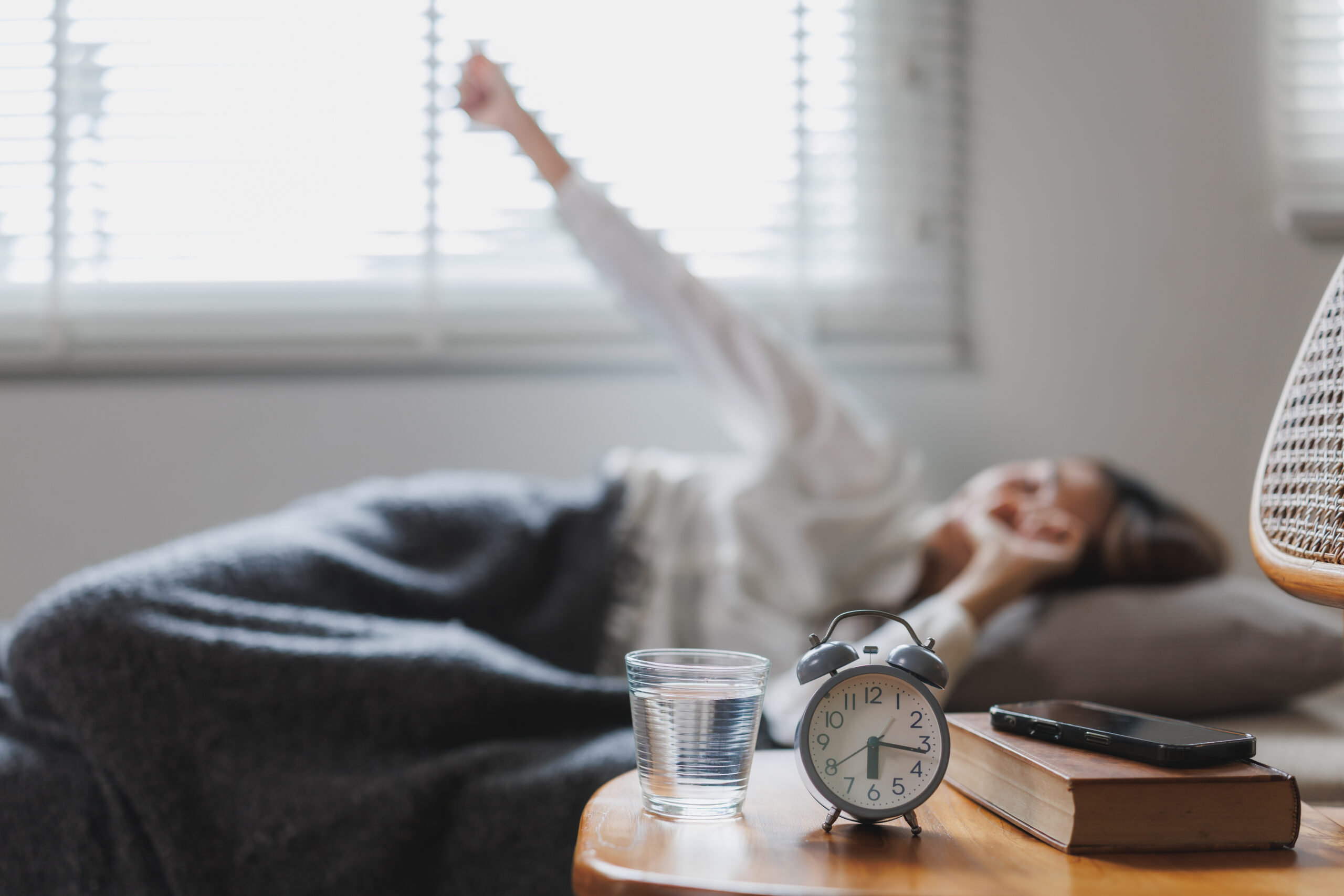 A woman waking up in bed looking exhausted yet alert.